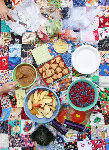 A colorful spread of health food on a patchwork picnic blanket